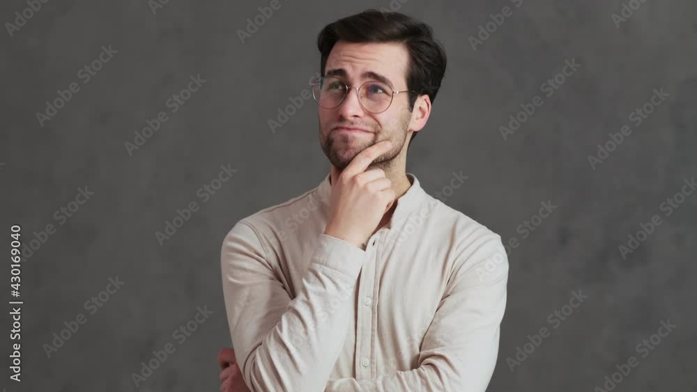 A pensive man in glasses thinking about something negatively shaking his head while spreading his hands in the studio A pensive man in glasses thinking about something negatively shaking his head while spreading his hands in the studio