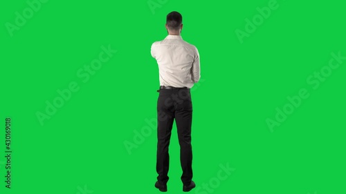 Back view of business man using interactive touch screen interface with various gestures. Full length on green screen chroma key background