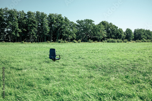 office chair standing in field in front of trees