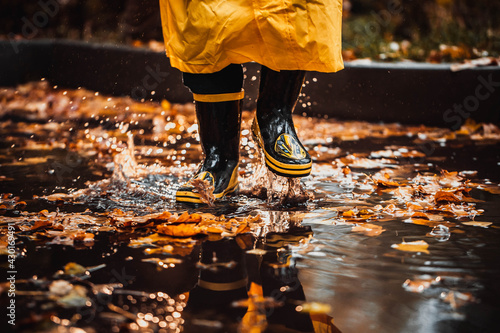 the child jumps into a puddle. legs in yellow rubber boots.