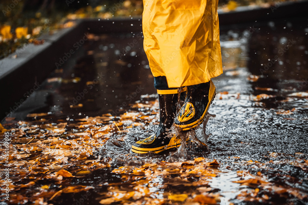 the child jumps into a puddle. legs in yellow rubber boots. the child jumps into a puddle. legs in yellow rubber boots.