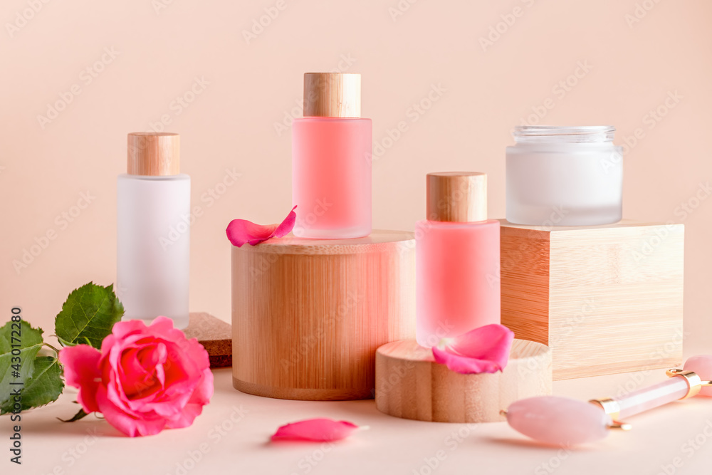 Facial serum and cream with rose extract on wooden podiums Facial serum and cream with rose extract on wooden podiums