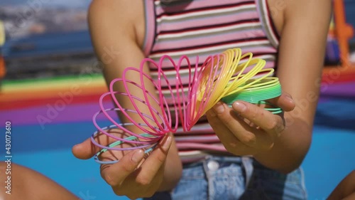 Beautiful young girl playing with a rainbow slinky against a background of colorful bright photo