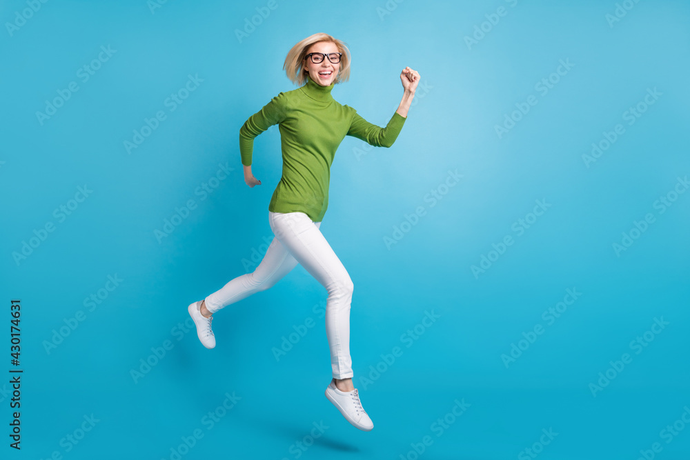 Full size photo of young happy positive smiling girl running fast speed in air isolated on blue color background