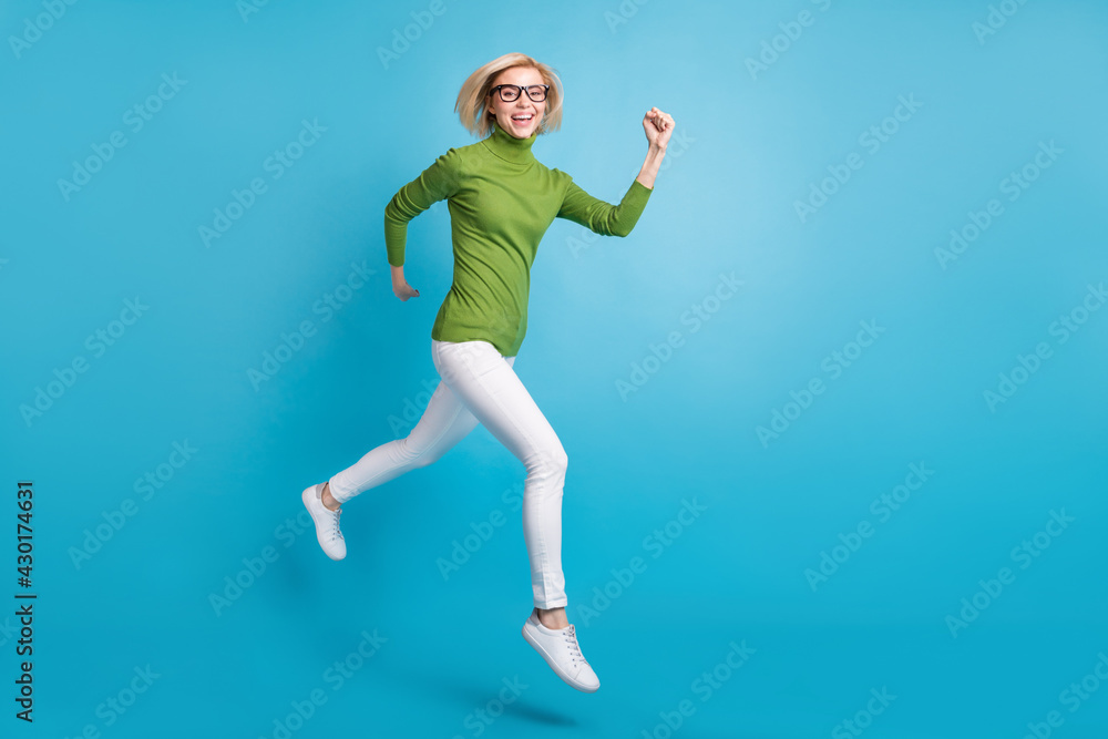 Full size photo of young happy positive smiling girl running fast speed in air isolated on blue color background Full size photo of young happy positive smiling girl running fast speed in air isolated on blue color background