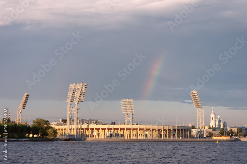 View on the stadium in Saint-Petersburg litten by setting sun from the Neva river with rainbow in the sky above the cityscape photo