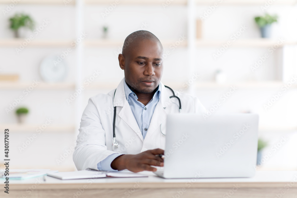 Modern medicine. Highly qualified african american therapist consultating patients distantly from his office Modern medicine. Highly qualified african american therapist consultating patients distantly from his office