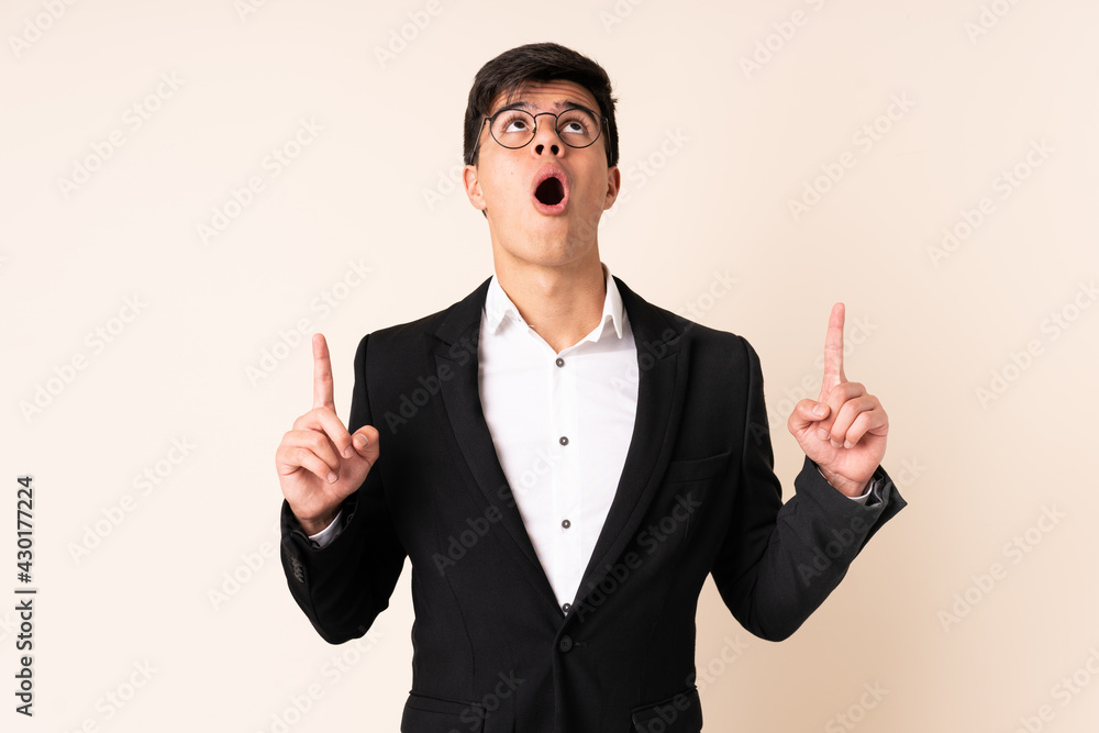 Businessman over isolated beige background pointing with the index finger a great idea Businessman over isolated beige background pointing with the index finger a great idea