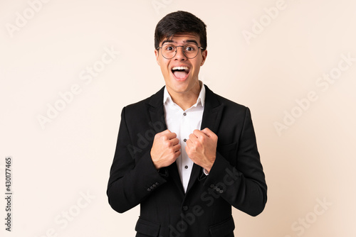 Businessman over isolated beige background celebrating a victory