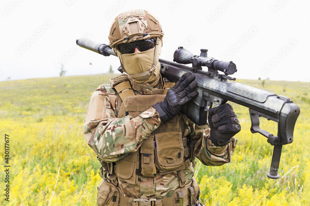 Special forces soldier walks across the yellow field with sniper rifle close up Special forces soldier walks across the yellow field with sniper rifle close up