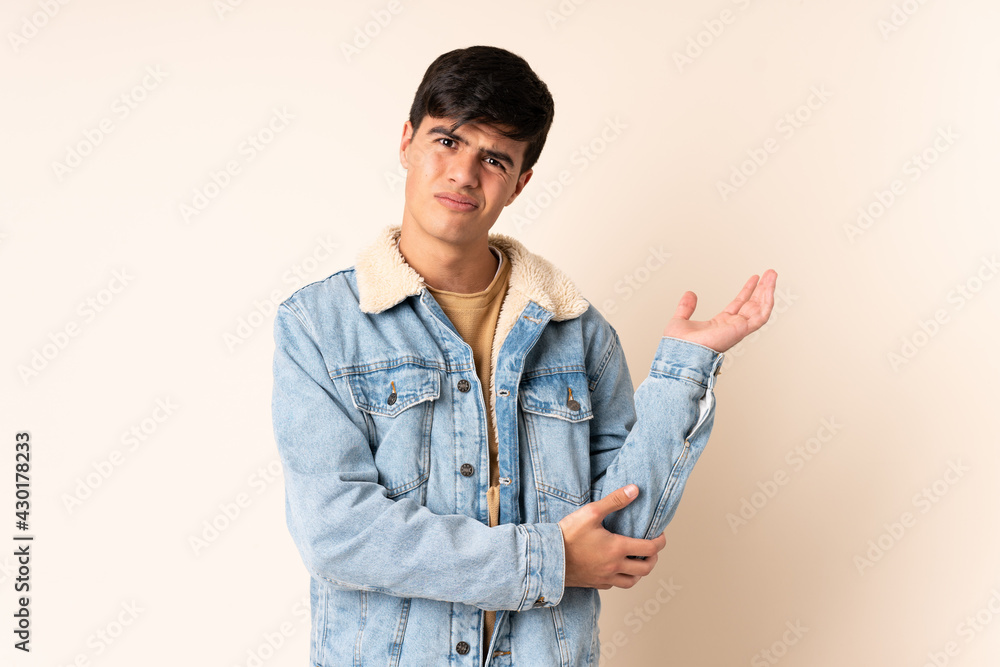 Handsome man over isolated beige background having doubts Handsome man over isolated beige background having doubts