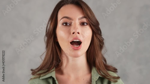 A close-up shot of a smiling woman showing grimace in the gray studio