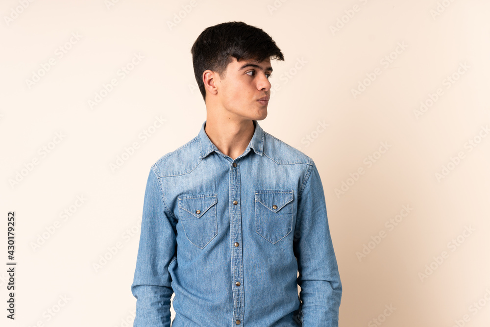 Handsome man over isolated beige background looking to the side Handsome man over isolated beige background looking to the side