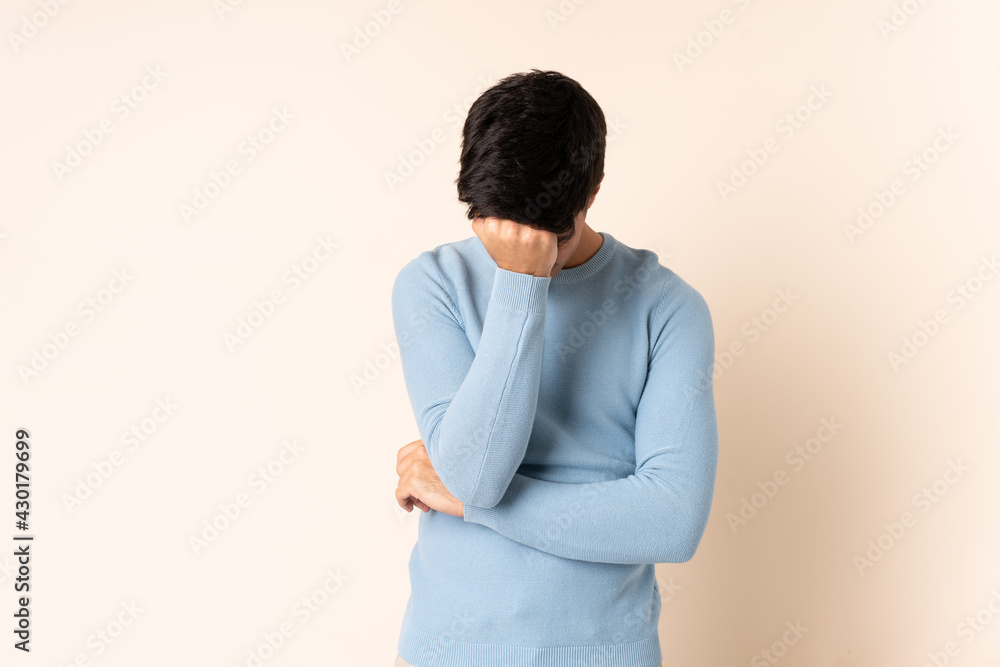 Handsome man over isolated beige background with headache Handsome man over isolated beige background with headache