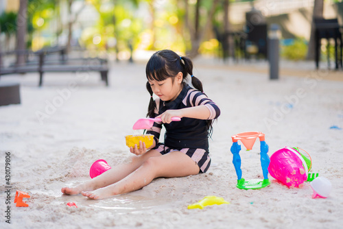 adorable child girl with sand toys in sandbox. Outdoor creative activities for kids
