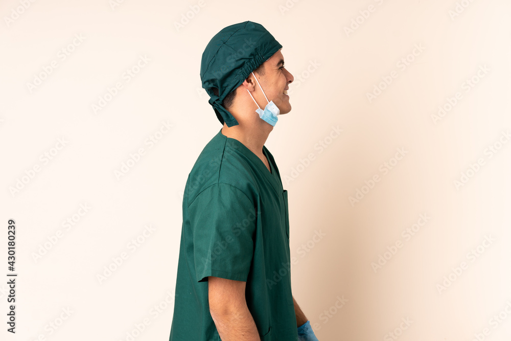 Surgeon man in blue uniform over isolated background looking to the side Surgeon man in blue uniform over isolated background looking to the side