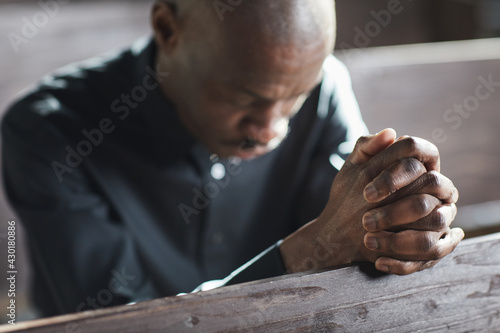 African man sitting with eyes closed and praying in the church © Seventyfour