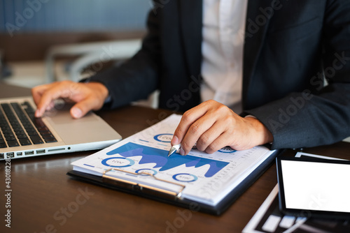 Businessman using digital laptop analyzes business data, busy working on tablet and business report on office desk, business strategy analysis concept.