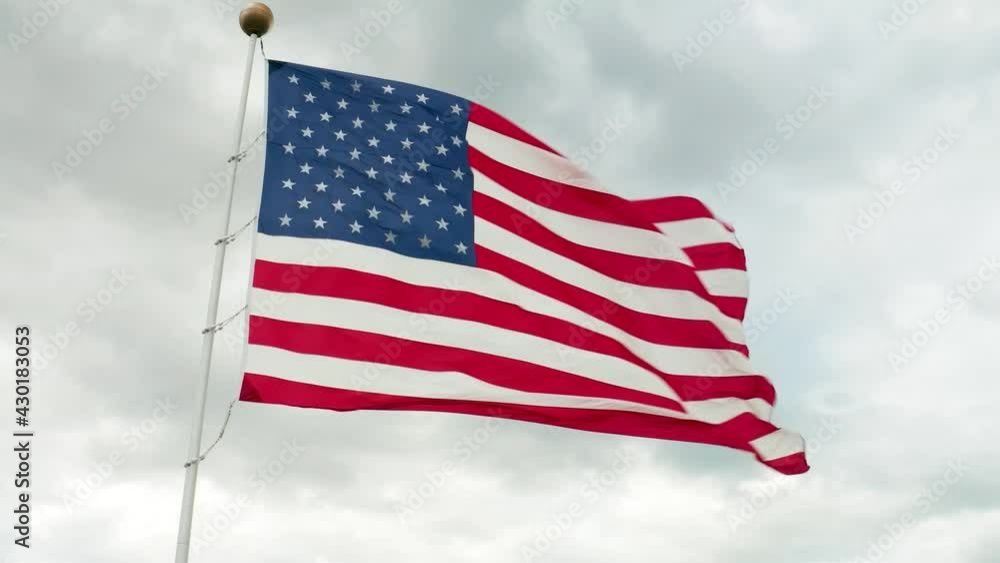 Aerial of American flag waving in wind against gray storm clouds in sky. USA pride, American values. Aerial of American flag waving in wind against gray storm clouds in sky. USA pride, American values.