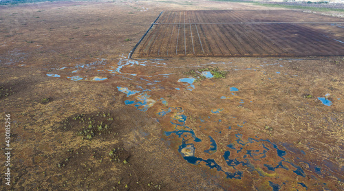 Aerial view to the new drainage network establishment for peat extraction field, next to the natural peat bog wetland. It is big environmental concern, and  source of greenhouse gases and biodiversity