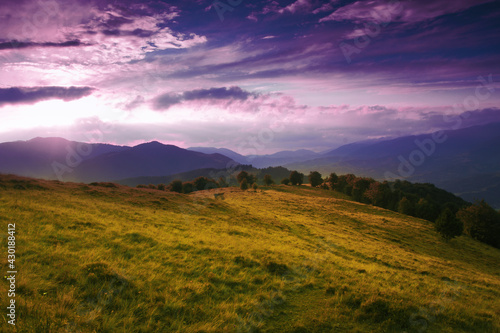 Europe moutains view, picturesque evening summer sunset landscape on meadow on slope of mountain on background of valley and wonderful sunset dramatic sky, scenic nature scene, Carpathians, Ukraine