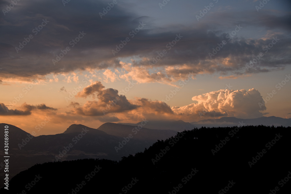 view of sky with big colorful clouds over mountain silhouette. Beauty in nature.