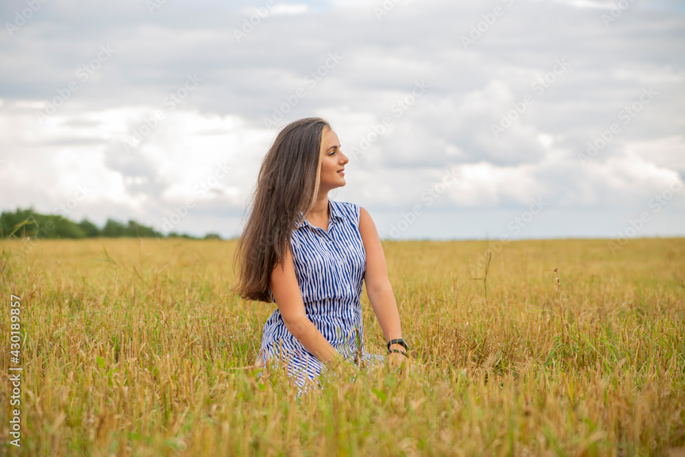 beautiful swarthy young woman sits in a meadow on a sunny day and enjoys the summer weather beautiful swarthy young woman sits in a meadow on a sunny day and enjoys the summer weather