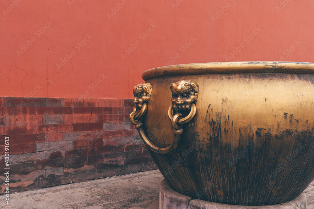 Golden water tank with lion statue against red wall in the Forbidden city Golden water tank with lion statue against red wall in the Forbidden city