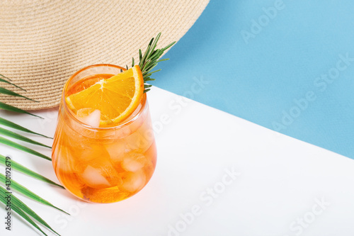 aperol in an ice glass, beach hat, leaf, blue and white background, space for text