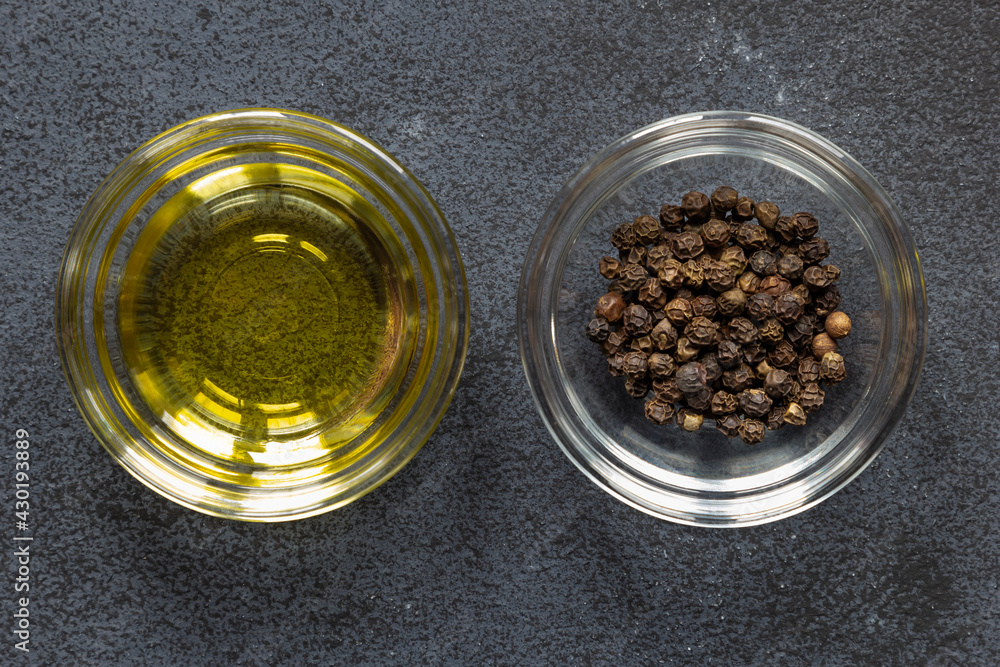 Black papper corn spice and olive oil in bowl on dark background Black papper corn spice and olive oil in bowl on dark background