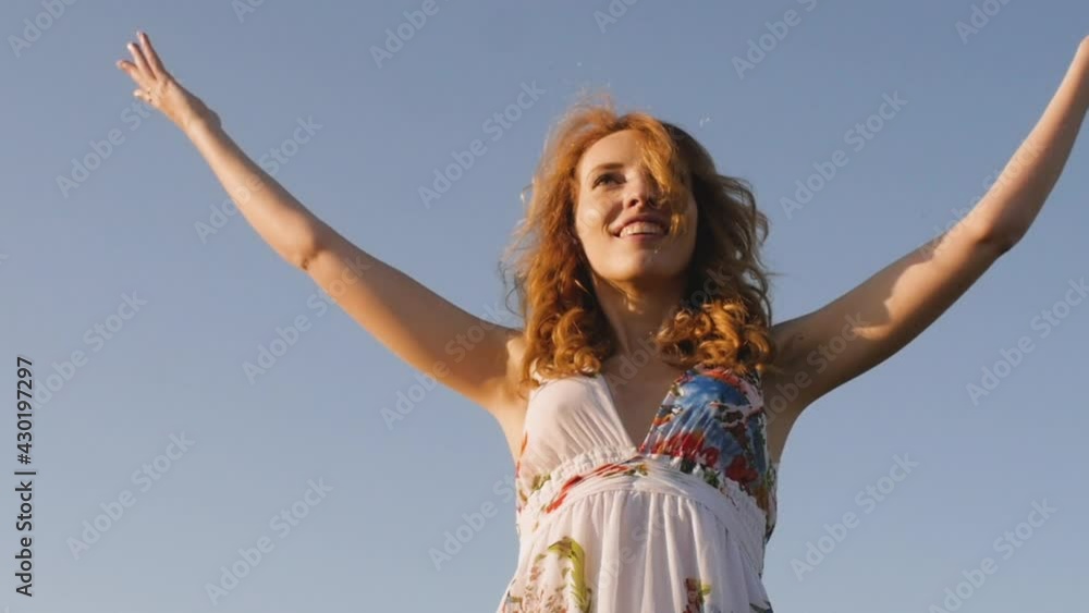 redhead young woman in white dress throws soft hearts on the background of the field. redhead young woman in white dress throws soft hearts on the background of the field.