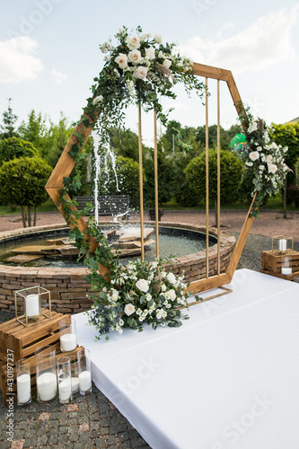 Vertical photo of wedding ceremony with arch in rustic style with fresh flowers