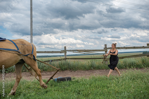 Young beautiful girl on the farm is engaged with a horse.