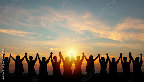 Silhouette of group business team making high hands over head in sunset sky