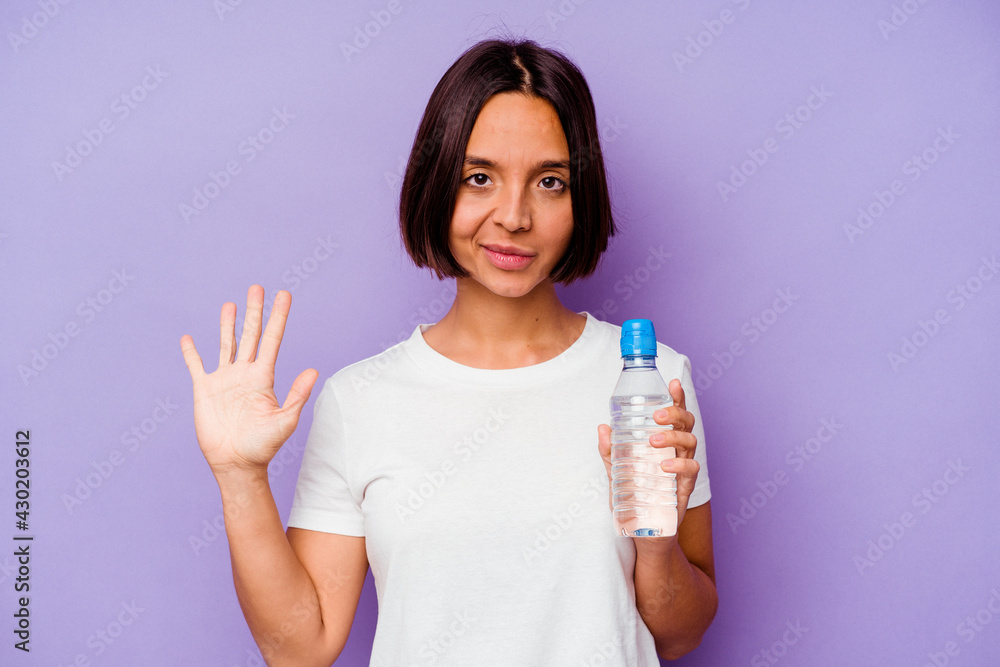 Young mixed race holding a water bottle isolated on purple background smiling cheerful showing number five with fingers. Young mixed race holding a water bottle isolated on purple background smiling cheerful showing number five with fingers.