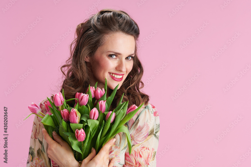 Portrait of smiling 40 years old woman in floral dress on pink