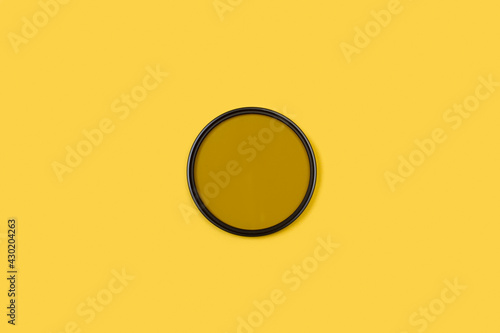 Filtro polarizador para la cámara sobre un fondo amarilloliso y aislado. Vista superior. Copy space photo