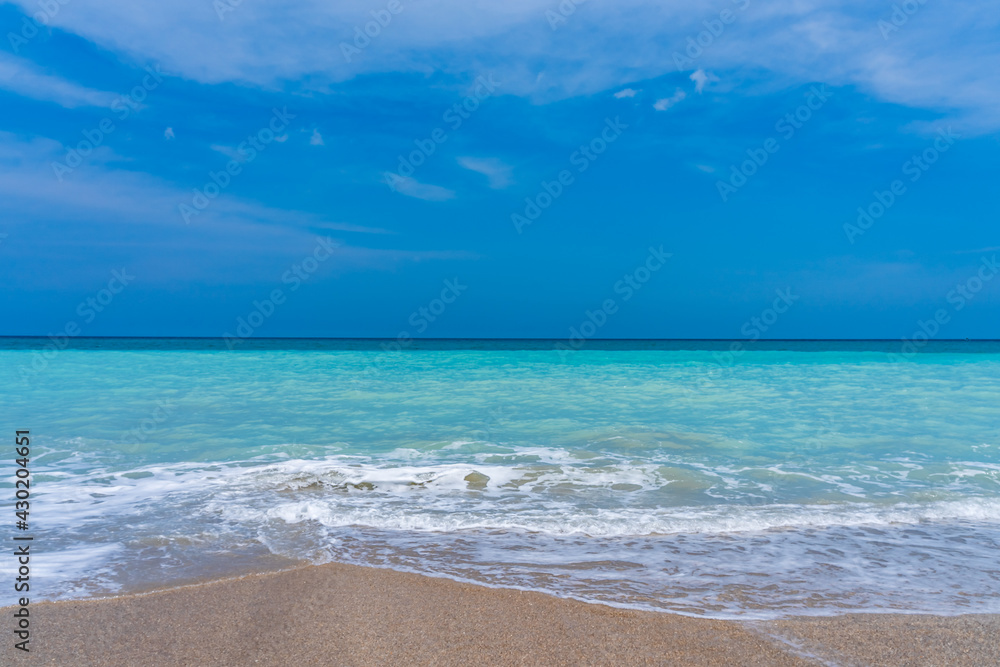 Panorama of an ocean beach in Florida in the spring. Turquoise ocean and a shallow white wave runs over the sand