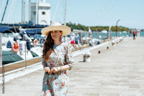 trendy solo traveller woman in floral dress on pier