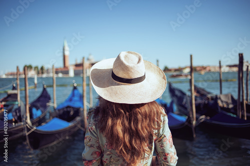 Seen from behind elegant woman in floral dress with hat © Alliance
