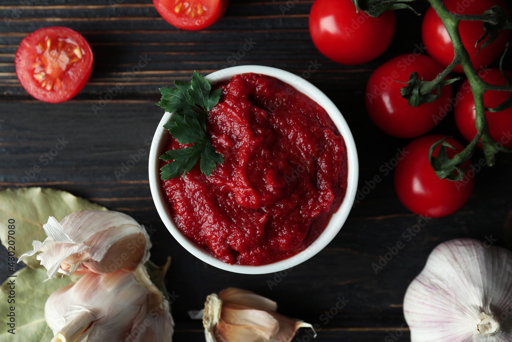 Bowl with tomato paste, tomatoes and garlic on wooden table Bowl with tomato paste, tomatoes and garlic on wooden table