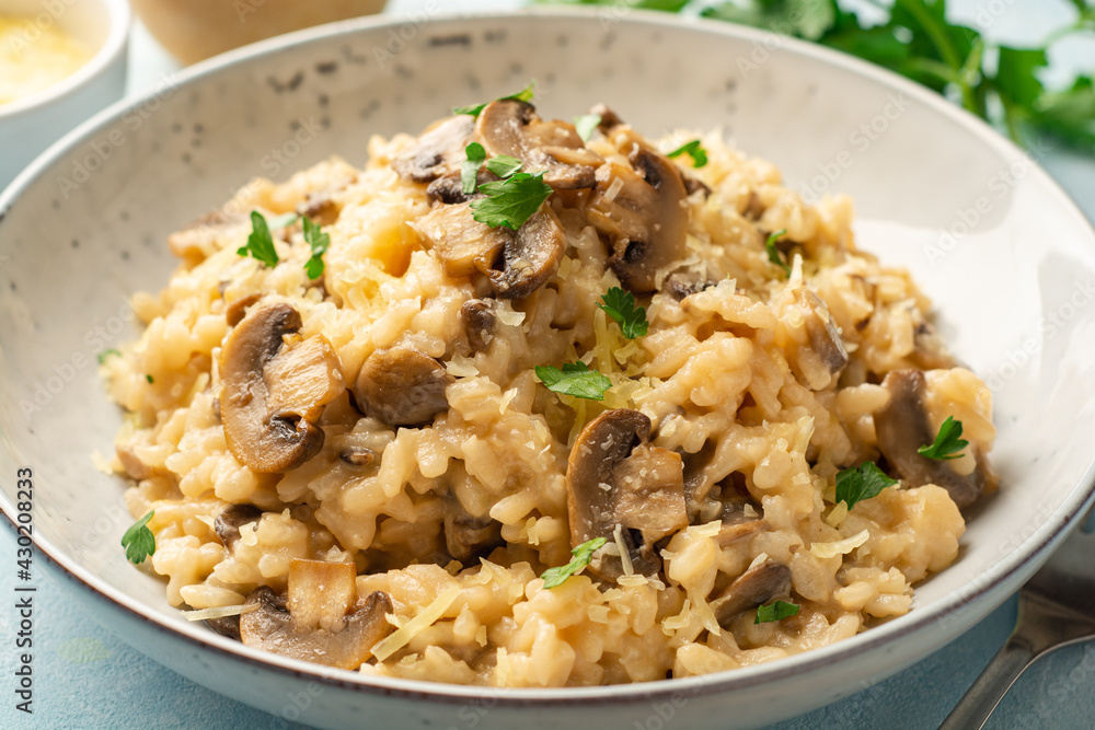 Risotto with mushrooms, parmesan cheese and parsley in plate on concrete background Risotto with mushrooms, parmesan cheese and parsley in plate on concrete background
