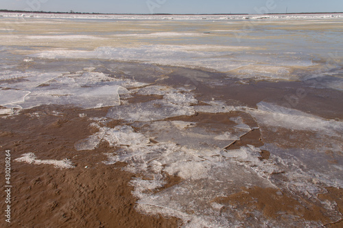 natural background early spring on the river, the beach is covered with a crust of ice