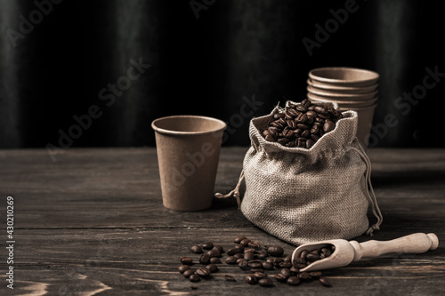 Bag full of coffee beans and sprinkled coffee on a wooden table with copy space. Concept for advertising background for cafe. 