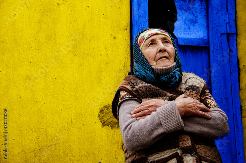 An elderly woman in a poor area. Grandmother on a yellow background. The old grandmother in the background of the slums. Helping vulnerable populations. Poverty and disadvantage concept. Grandmother