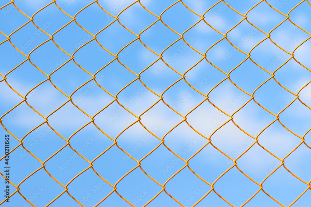 Yellow metal grid on the blue sky background. Sunny summer weather on the sport court Yellow metal grid on the blue sky background. Sunny summer weather on the sport court