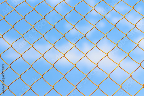 Yellow metal grid on the blue sky background. Sunny summer weather on the sport court