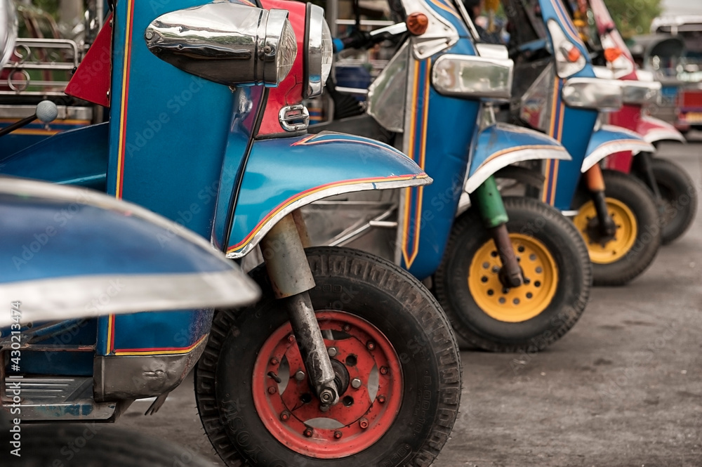 Asian Moto Taxi Tuk Tuk with Colorful Wheels lined up on the Street