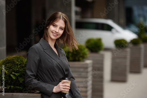 Portrait of a smiling businesswoman, outdoors.Beautiful girl with coffee.