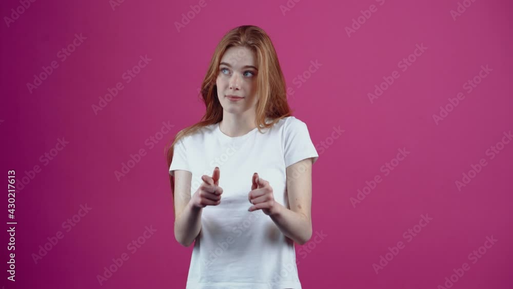 Are you ready. The shy and beautiful redhead looks embarrassingly with both index fingers in front and then displays a wide smile. Freckled teenage girl in a white T-shirt, isolated on a pink Are you ready. The shy and beautiful redhead looks embarrassingly with both index fingers in front and then displays a wide smile. Freckled teenage girl in a white T-shirt, isolated on a pink